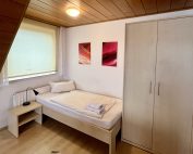 Monteurzimmer in Lippstadt mit Einzelbett, Kleiderschrank und Sitzbereich im Haus Stallmeister