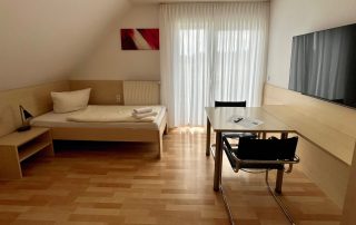 Monteurzimmer in Lippstadt mit Einzelbett, Fernseher, Tisch und Balkon